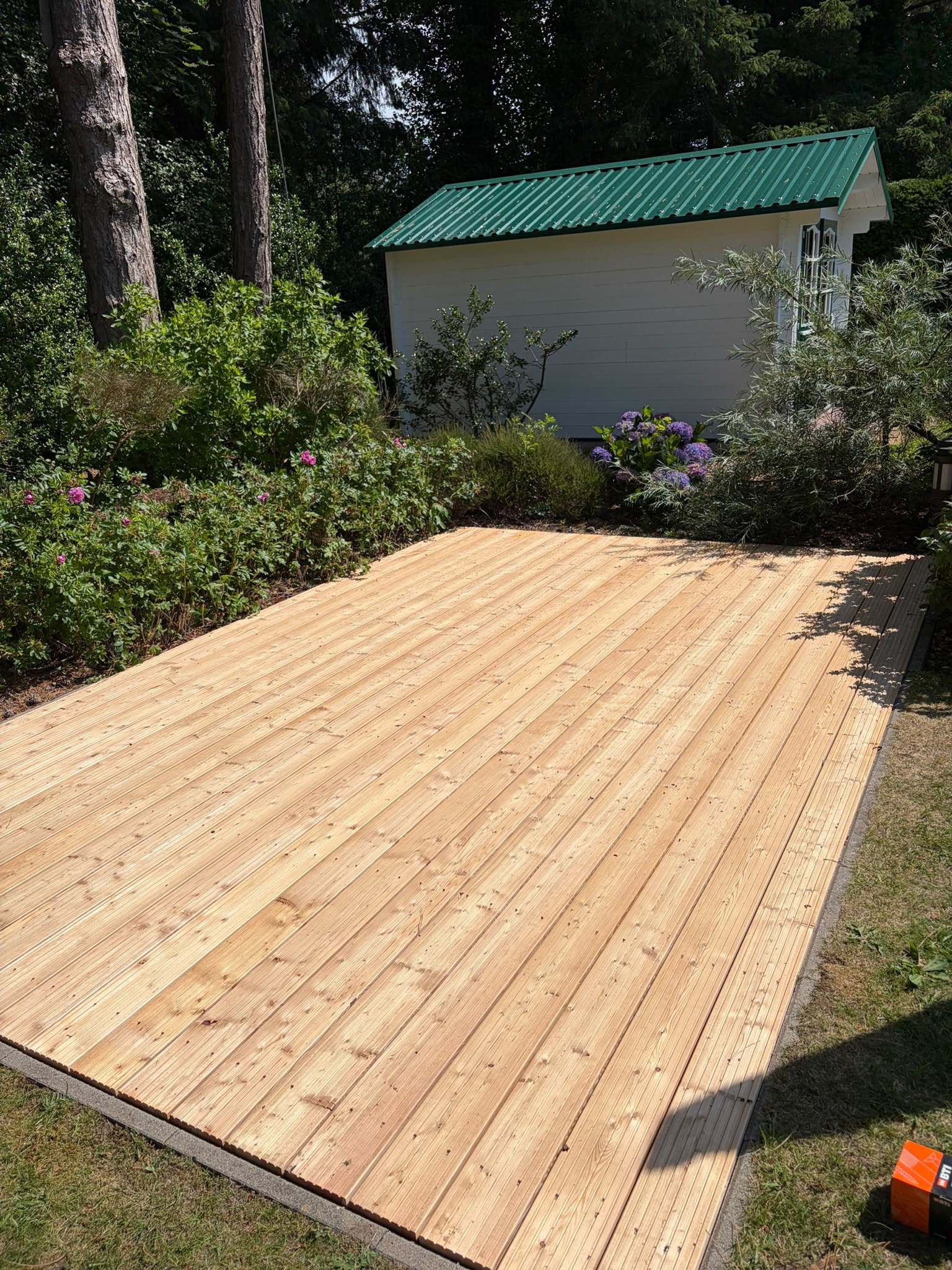 Neues Holzdeck aus Lärche zwischen Beeten im Garten