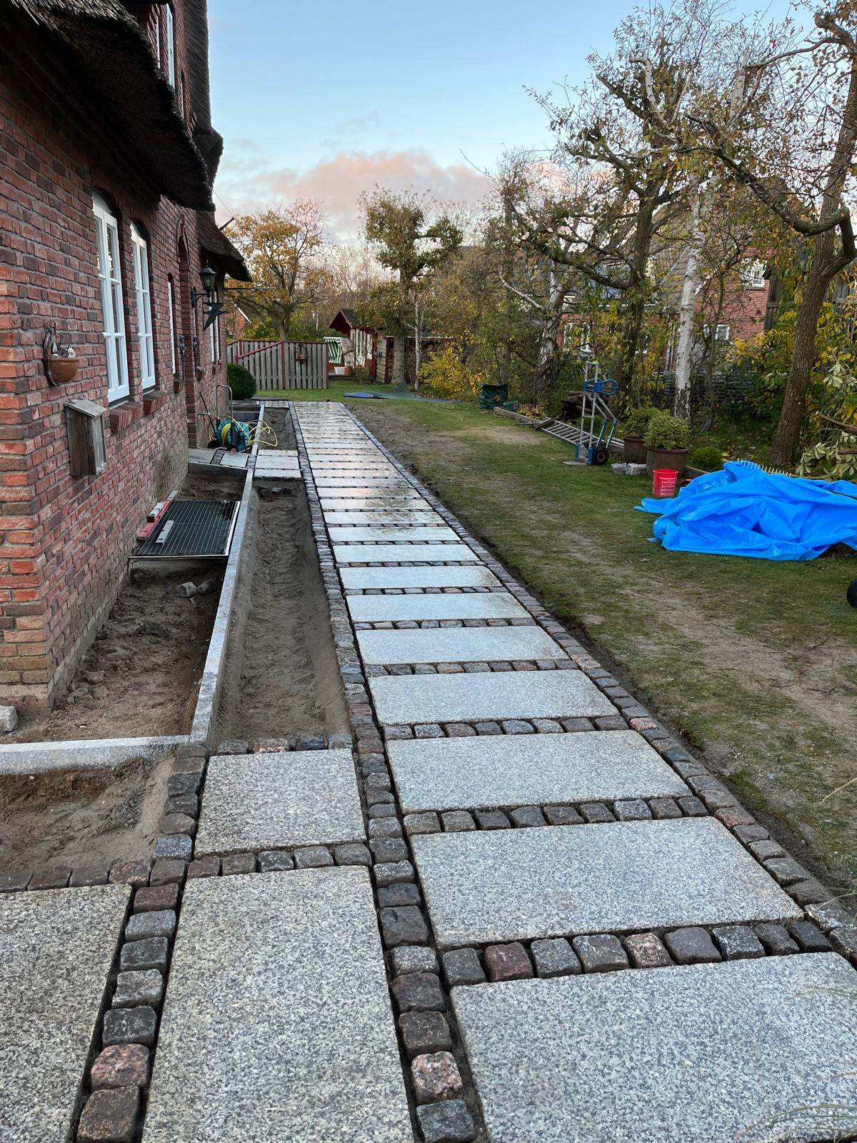Neu angelegter Granit-Pflasterweg an einem Reetdachhaus auf Amrum